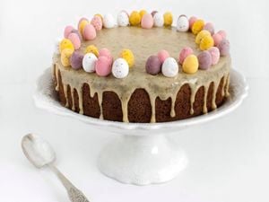 Chocolate cake decorated with Easter eggs on stand with white background.