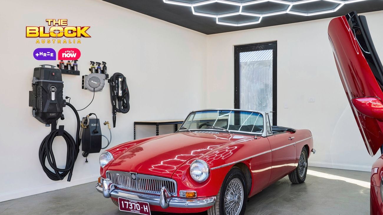 Garage from The Block with hexagonal LED ceiling lights, white walls, and a red sports car in it.