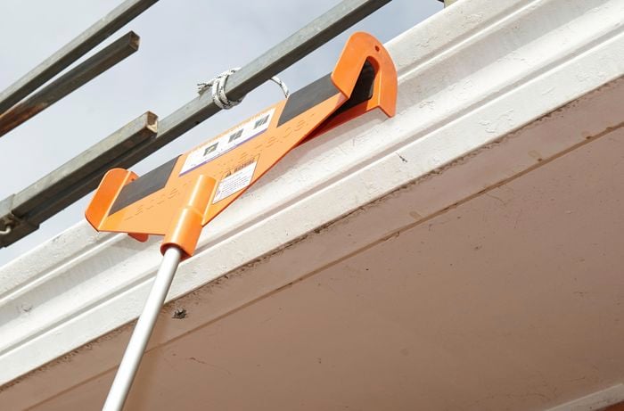 A ladder's little helper leaning against a roof gutter