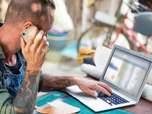 A close up of a man on his mobile phone and on a computer preparing for the steps to building a home.