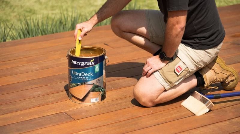Man with decking oil and brush on deck
