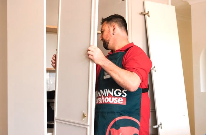 A person holding a cupboard door.