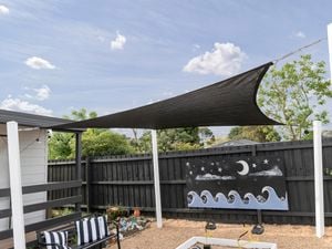 An installed black shade sail over a kindergarten sandpit