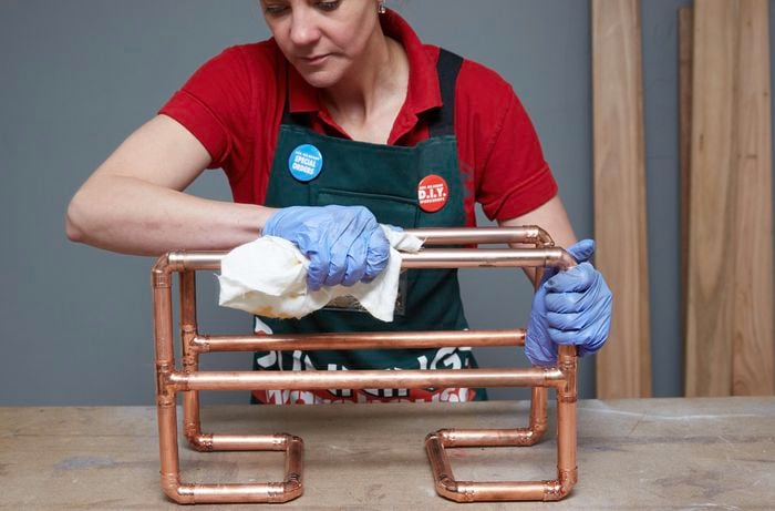 Person polishing copper magazine rack
