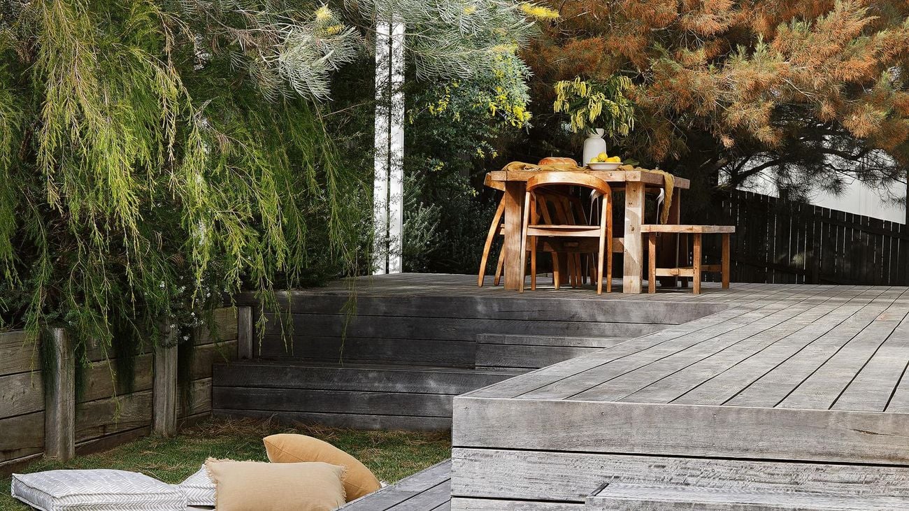 Grey timber deck in a lush backyard.