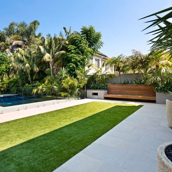 Pool surrounded by palm trees and fake turf.