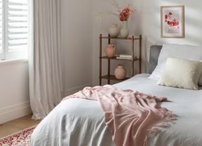 A bedroom with shutters, curtains, a textured rug and throws to keep your home warm
