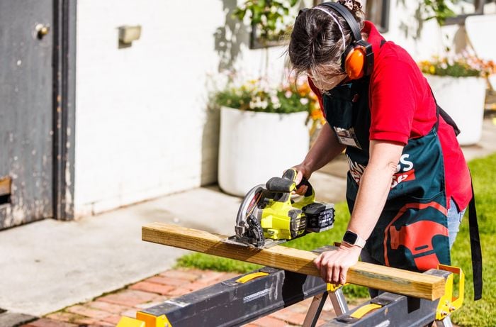 A person cutting studs wearing safety equipment.