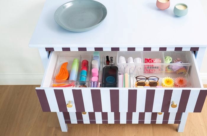 Open cabinet drawer revealing organised storage compartments filled with small household items.