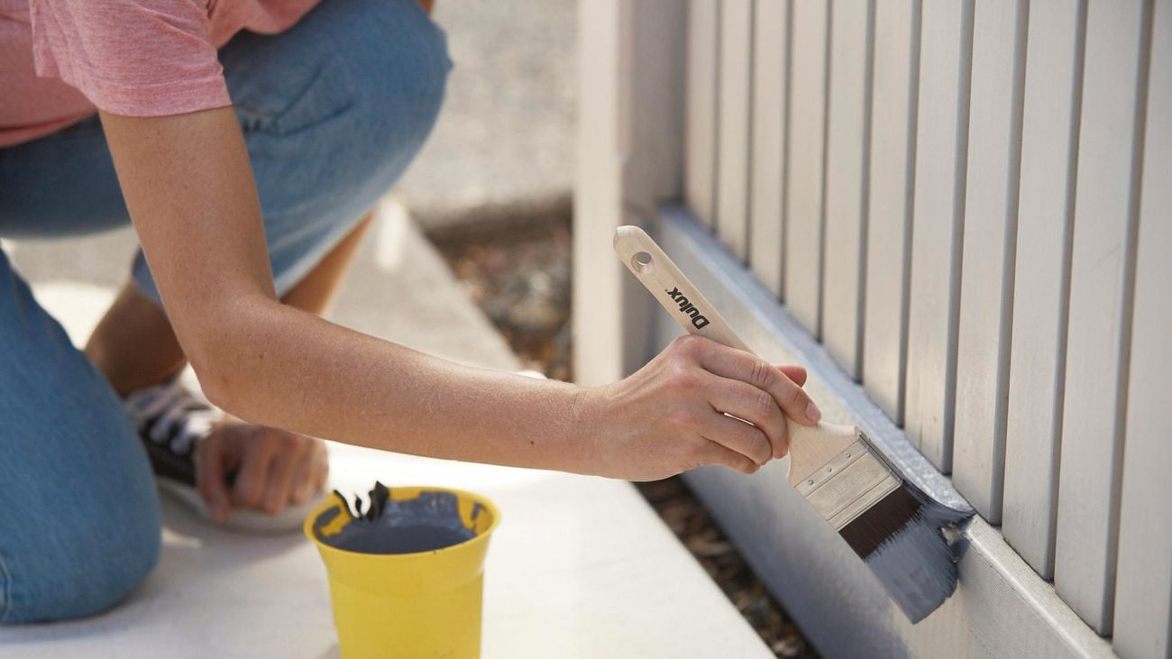 Hand painting skirting board with brush and blue paint