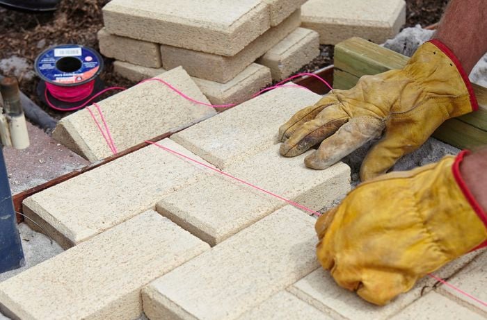 A person running a line of pink string over newly laid pavers