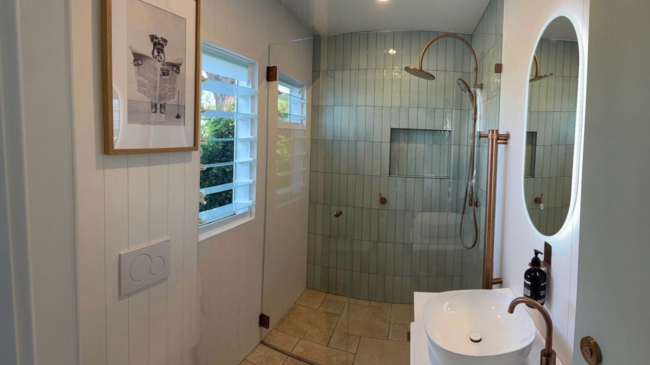 A bathroom with green tiles and white James Hardie wall cladding.