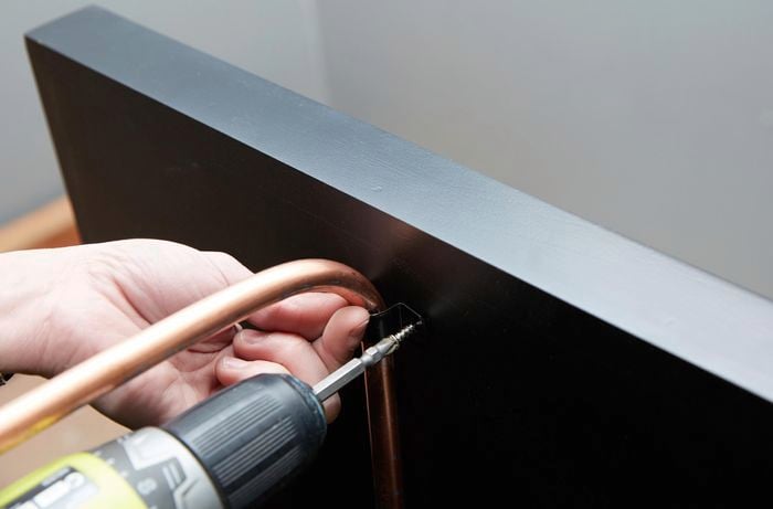 Person drilling screw into bracket to hold legs to tabletop