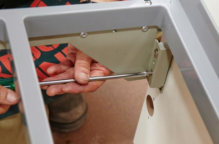 A person attaching the front panel to the basket using a screwdriver