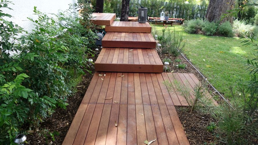 Tiered decking leading around the corner of a house, next to a lawn