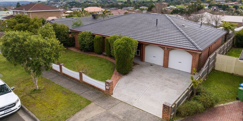 The front of a brick house with a car on the road out the front of the house