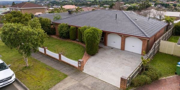 The front of a brick house with a car on the road out the front of the house