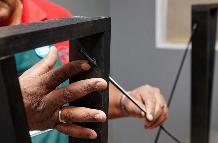 A person fitting threaded rod through table legs