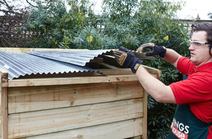 Corrugated iron being laid out over a roof frame by a Bunnings team member