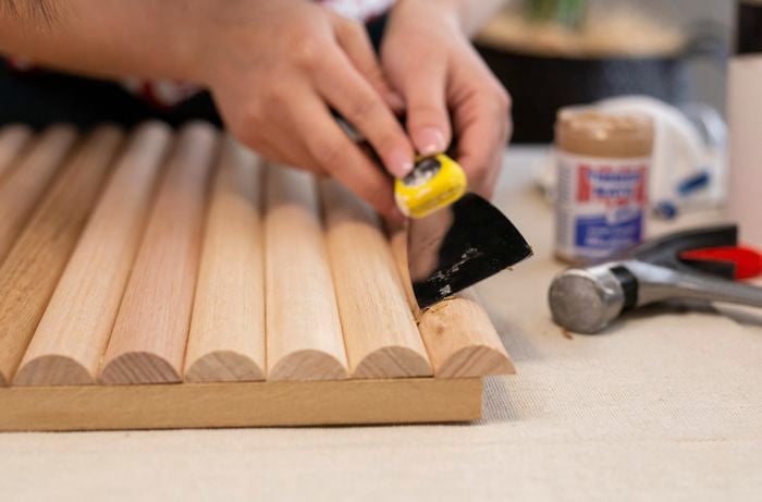 Person using steel blade to insert timber filler between timber dowels.