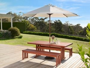 A backyard with a deck, outdoor table and an umbrella.