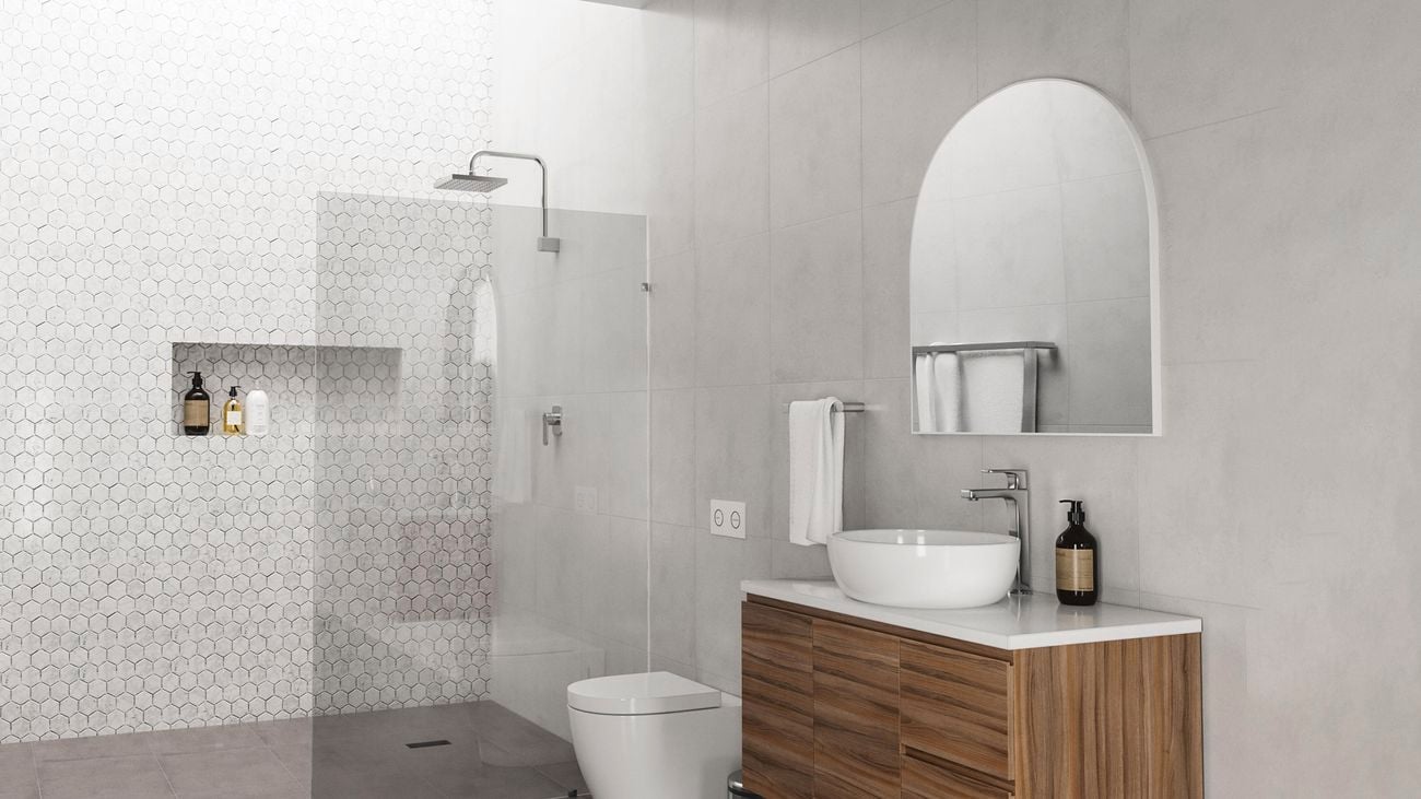 A spacious modern bathroom with a floating wooden countertop and mirror above it. A shower with a glass screen and toilet are in the background.
