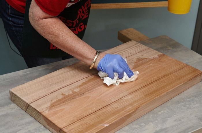 A person applying oil to a wooden cutting board