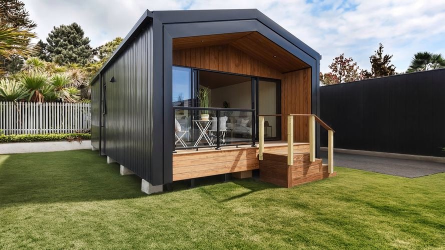 Modern black granny flat exterior with timber-lined porch, sliding doors and raised deck. Extra 2: Timber deck with outdoor seating