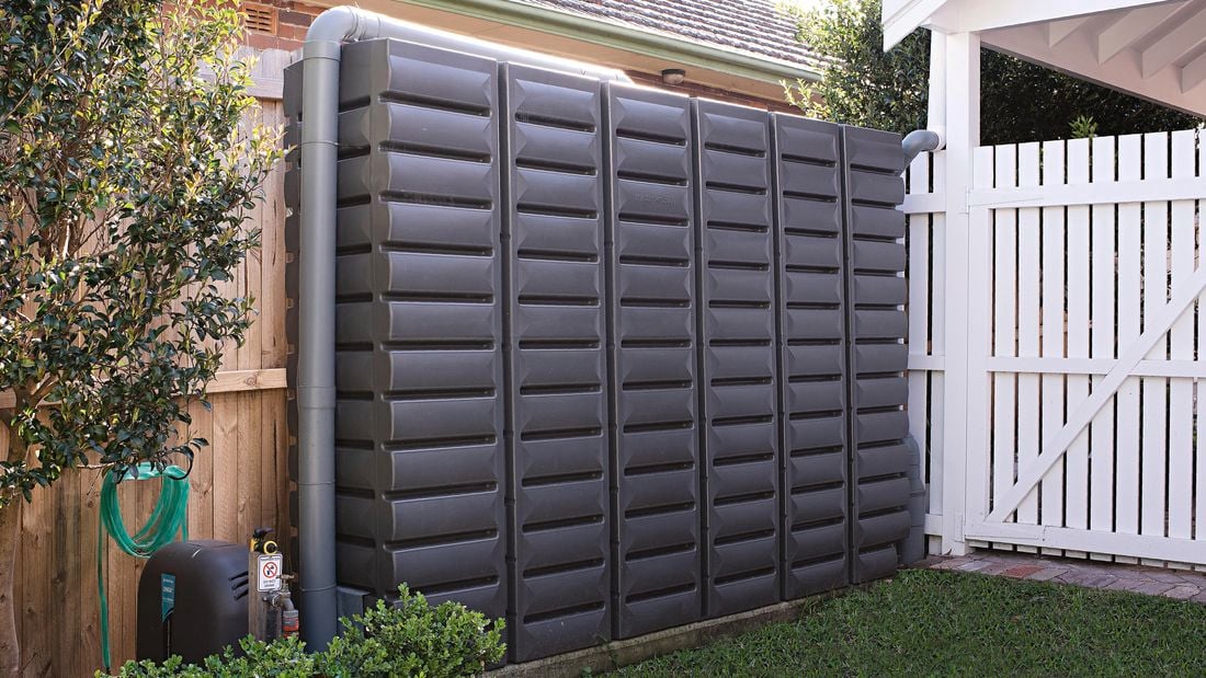 Water tank in the backyard near wooden fence.