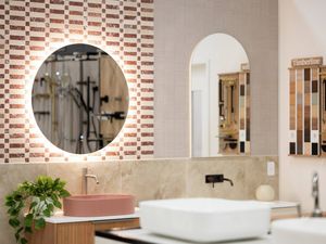 Bathroom showroom display with illuminated mirror, pink basin and tile samples.