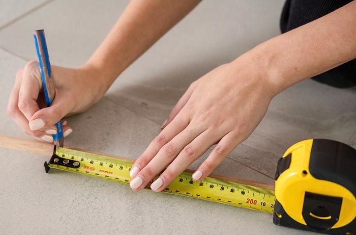 A dowel being measured and marked with a tape measure and pencil