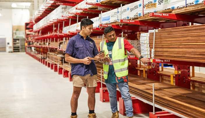 A Bunnings Warehouse team members shows a tradie how to use his PowerPass app in-store