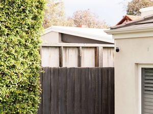 A Swann security camera is mounted on a house wall.