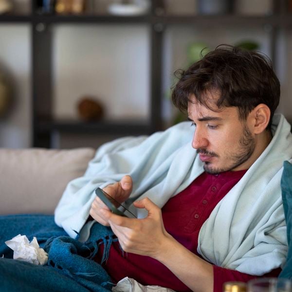 Man lying on a couch looking very relaxed and reviewing his phone