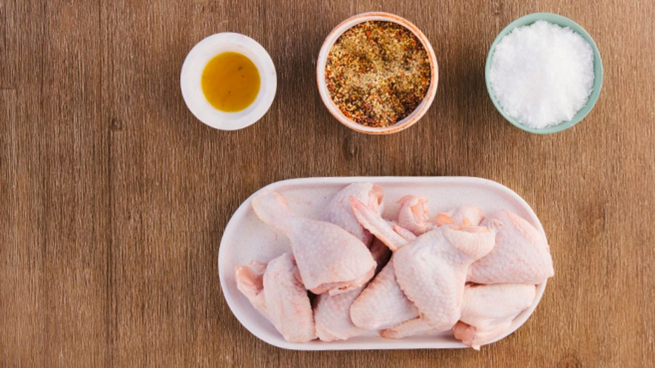 Chicken on a platter next to bowls of spices.