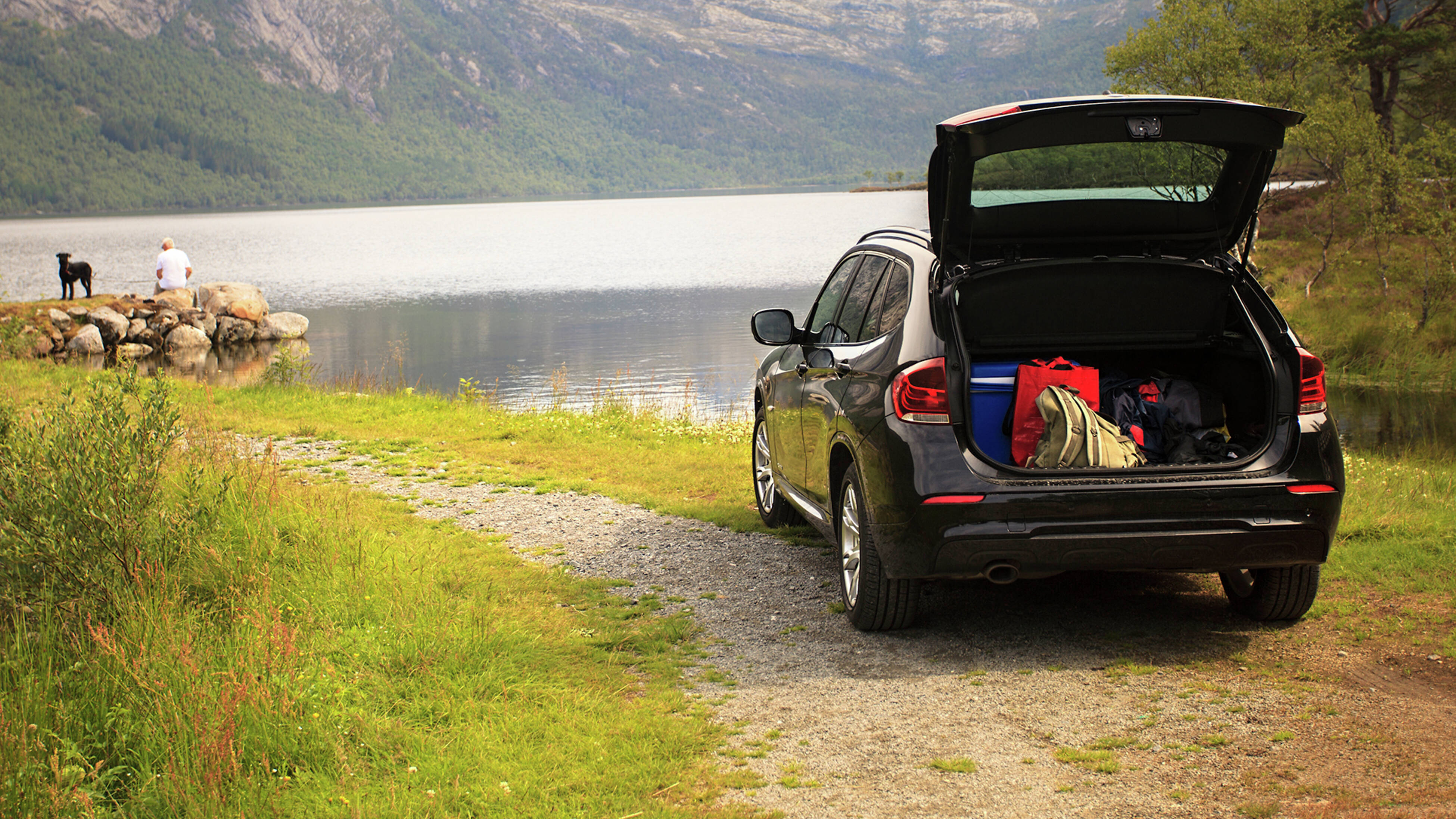 car parked at scenic spot with open boot displaying vehicle checklist items