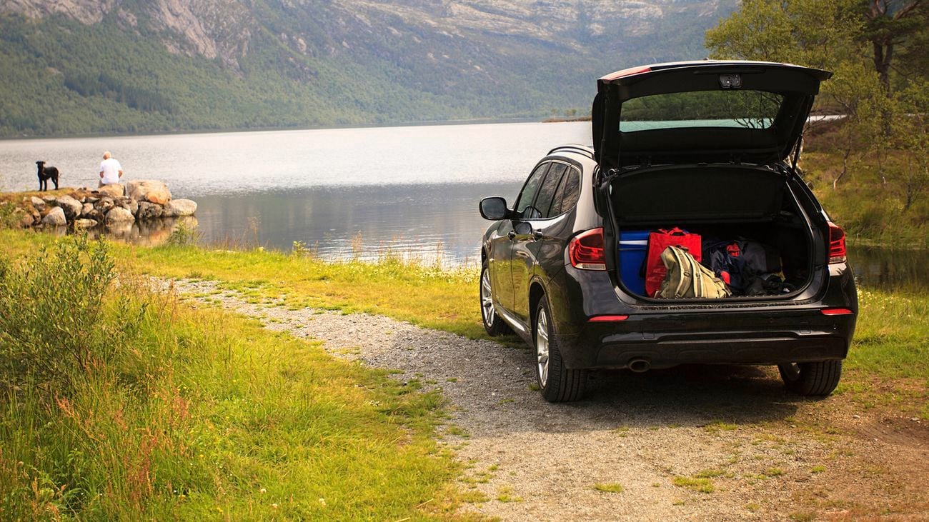 car parked at scenic spot with open boot displaying vehicle checklist items