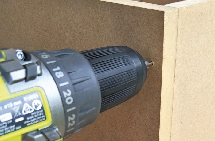 Drill being used to create holes in side of cabinet.