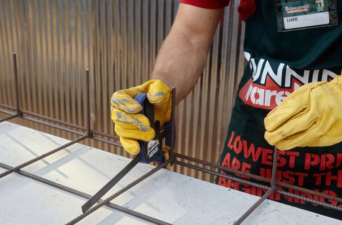 A Bunnings team member using clamps to keep two sheets of wire mesh close together for welding