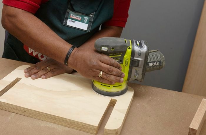 Person using orbital sander on wooden step piece.