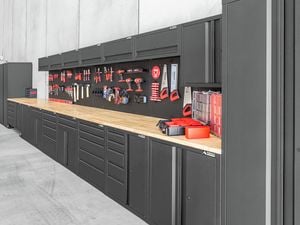Full range of a timber top black garage storage unit consist of a pegboard, workbench, cupboards, drawers and shelfs with tools