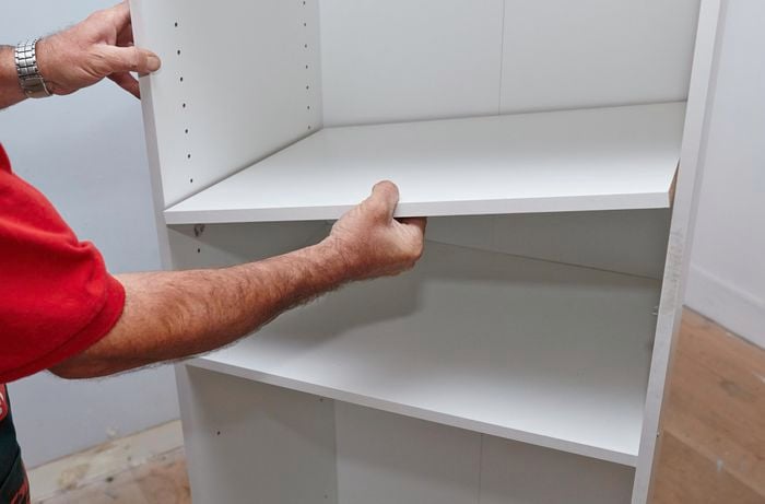 Person sliding wardrobe shelf in place.