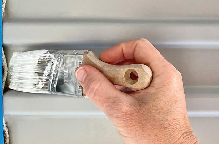 Angled brush with paint and painters tape on door.