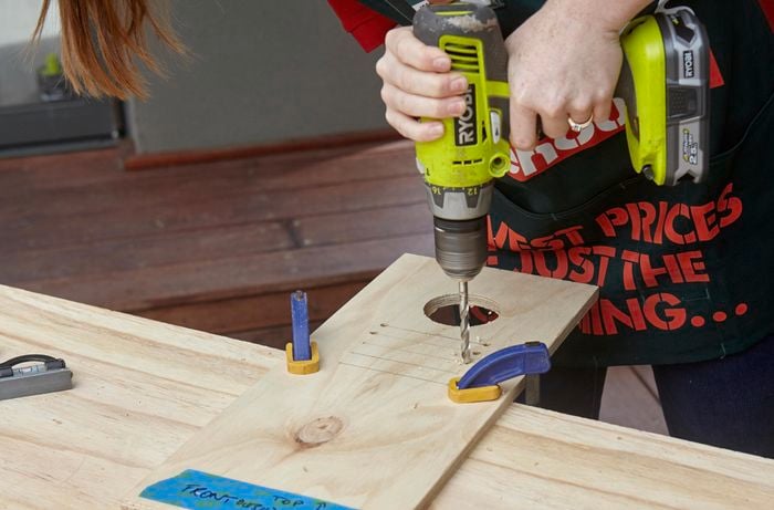Holes being drilled into a plank of wood for future jigsawing