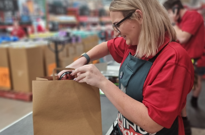 Bunnings team member in store packing product into brown paper bag