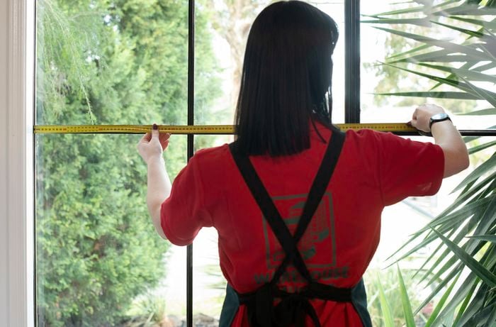 A person measuring the width of a window