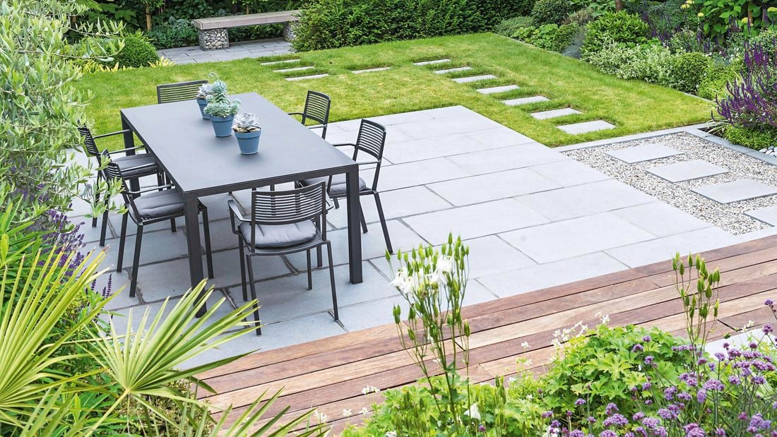 A completed outdoor dining area, complete with paved area, stepping stones and wooden benches