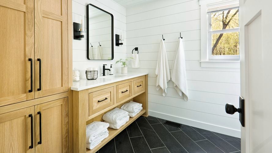 A modern bathroom with timber cupboards and marble white benchtop.
