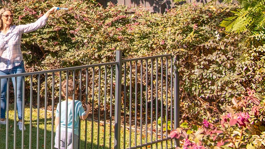Two kids and one lady playing in a garden surrounded by Rapid Fence.