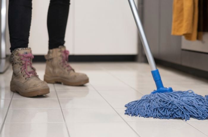 A person mopping the floor with cotton mop.